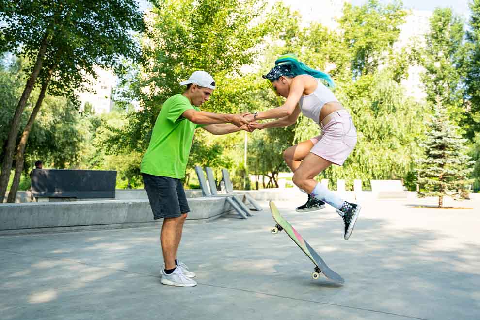 Jovem fazendo manobra de skate com apoio de amigo