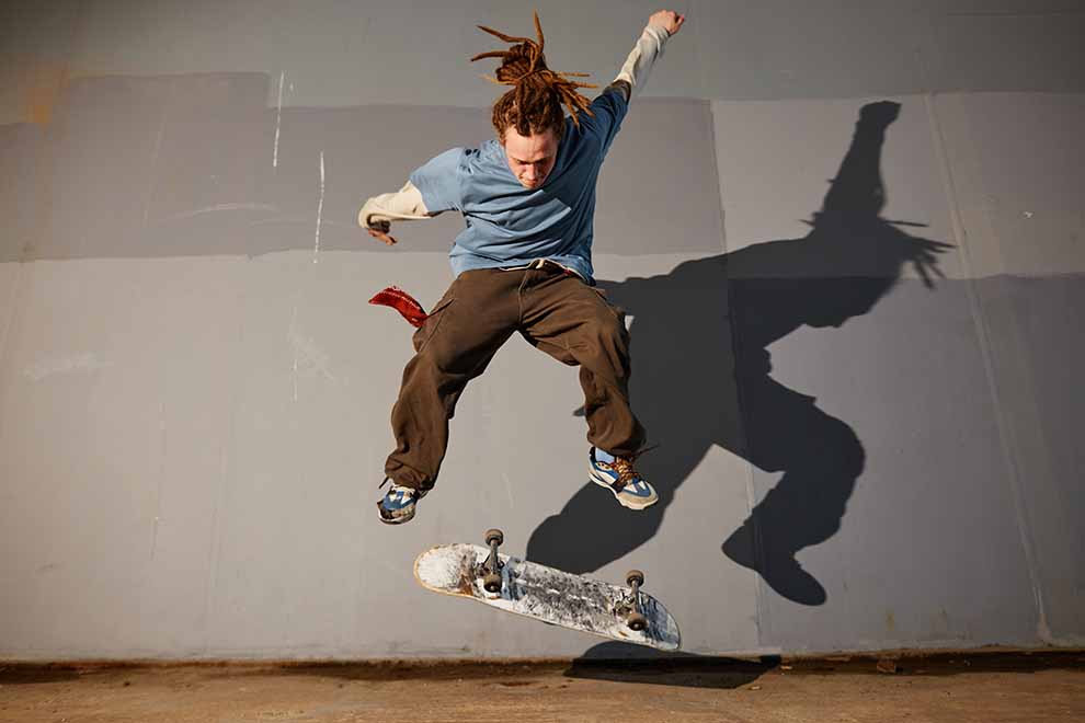 Skatista realizando manobra aérea em calça larga.