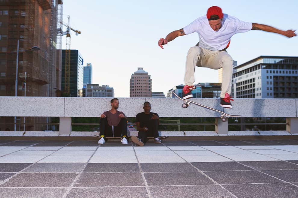 Skatista realizando manobra com amigos na cidade