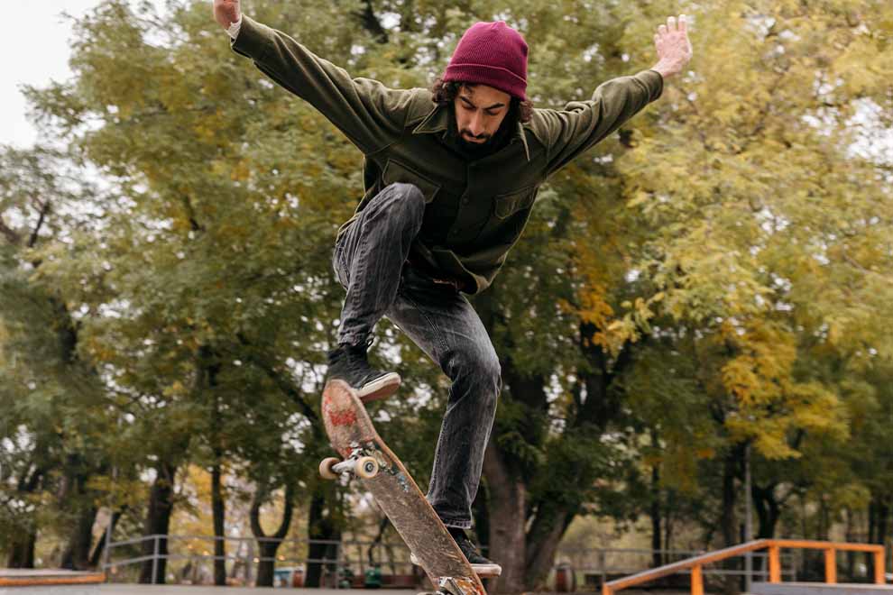 Skatista executando manobra em parque com árvores
