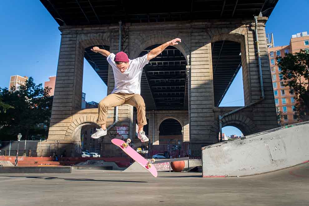 Skatista realizando manobra com prancha rosa.