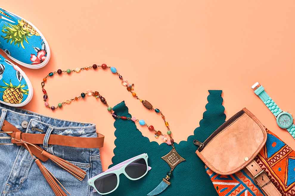 Conjunto de roupas e acessórios coloridos sobre fundo laranja.